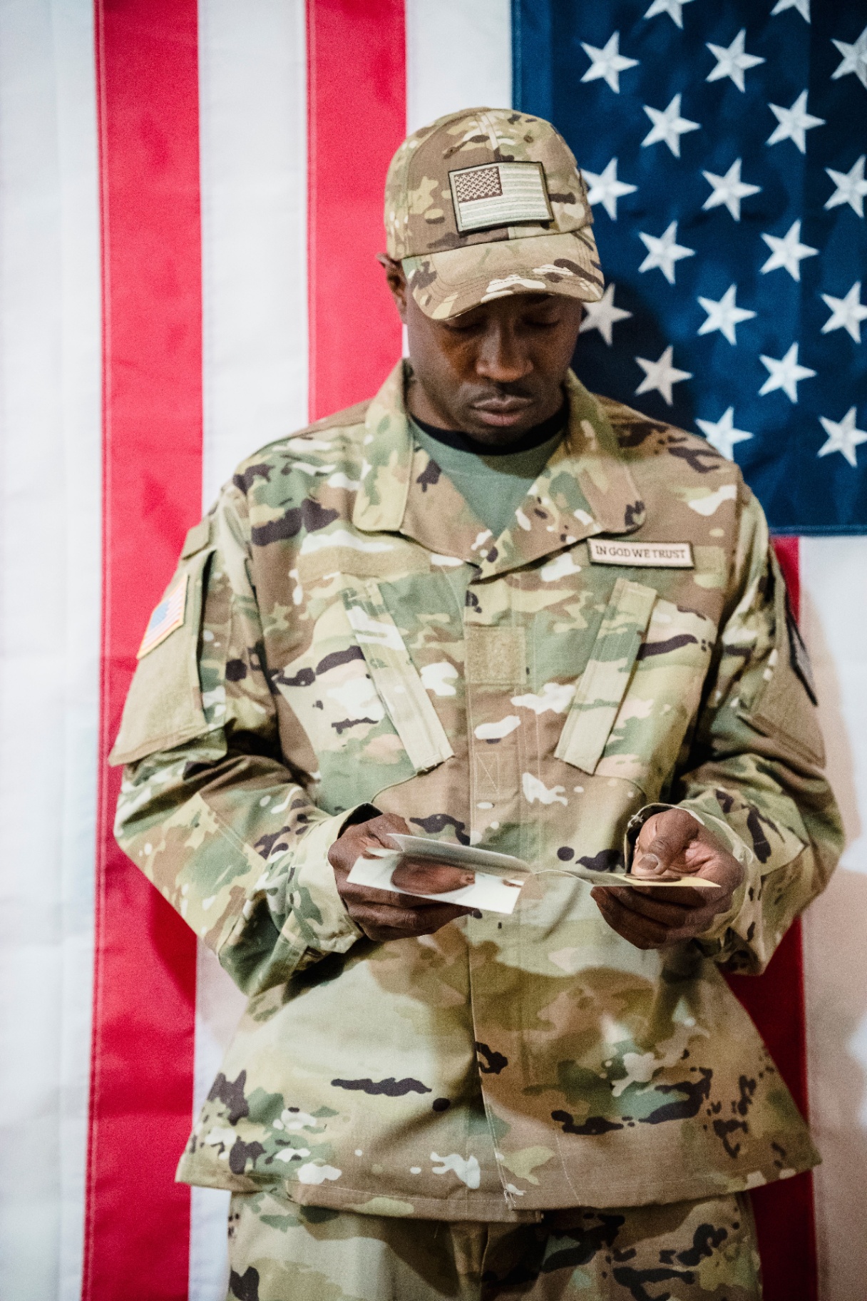 A U.S. service member reading a letter in front of the American flag
