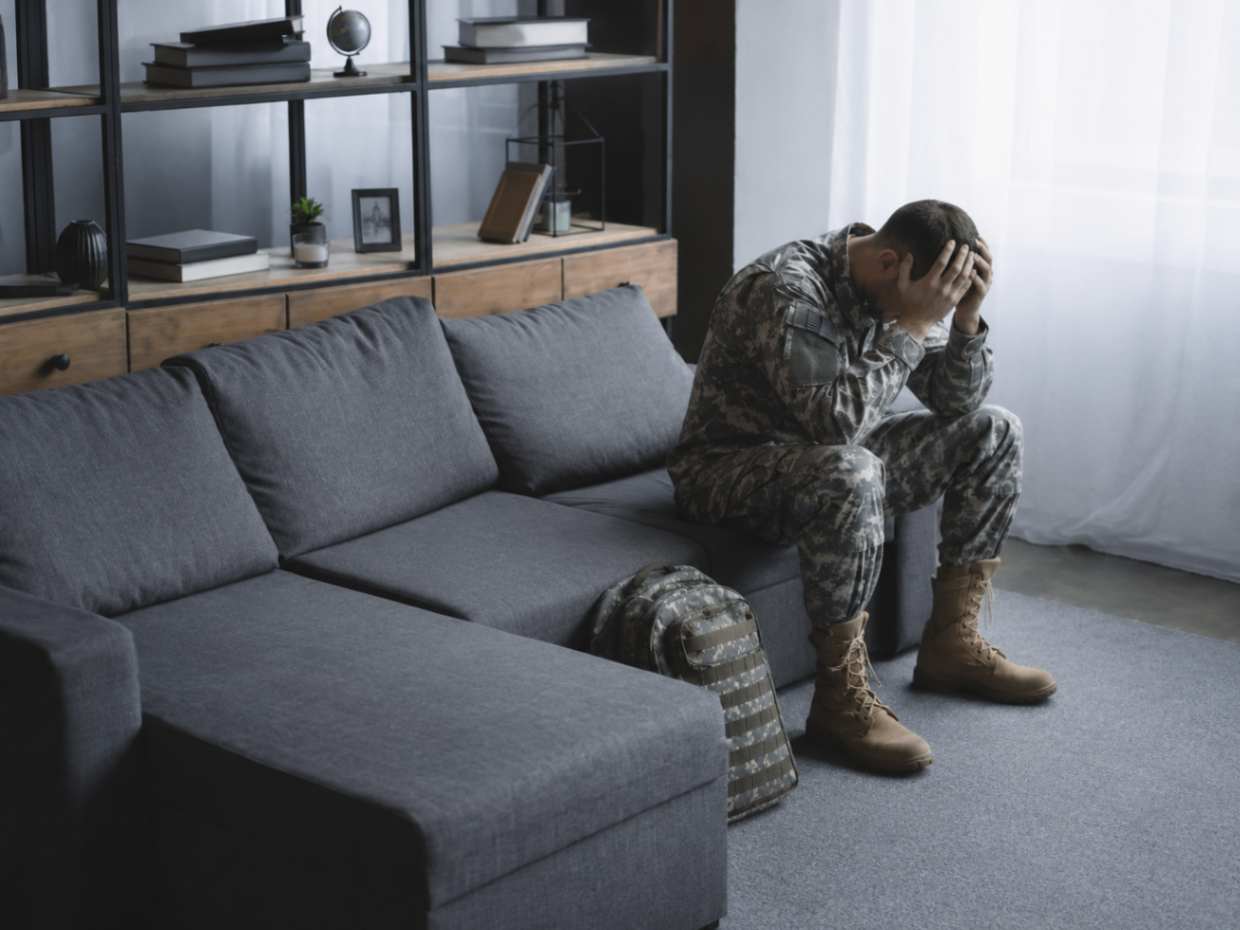 Veteran sitting on a couch with head in hands
