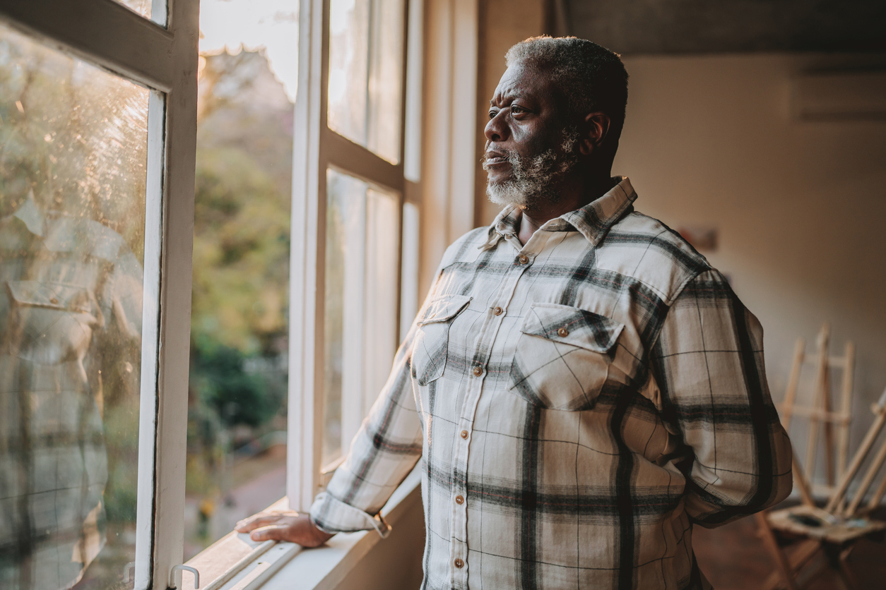 A veteran standing alone at a window, looking out