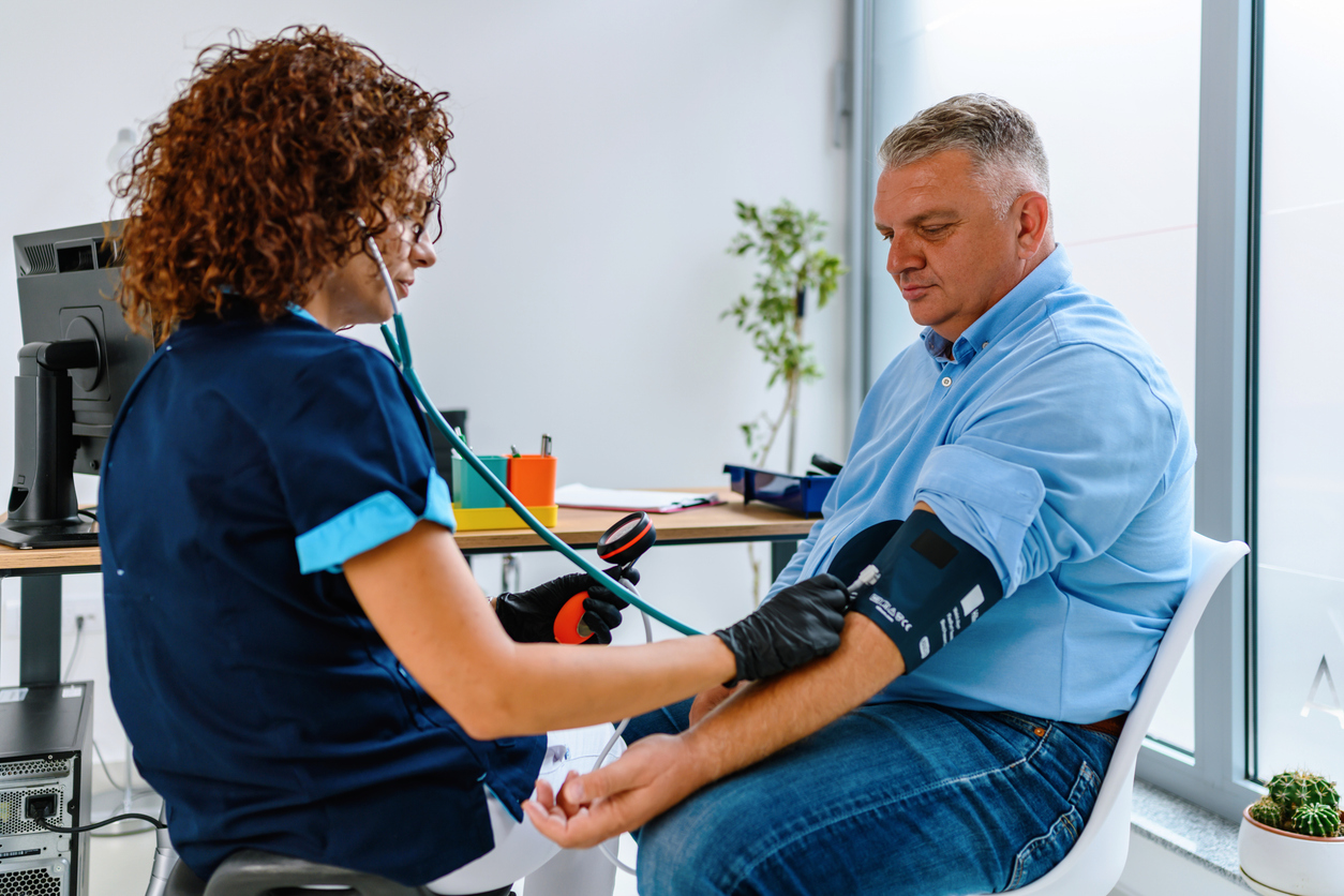 A nurse checking a veteran's blood pressure in a clinic exam room